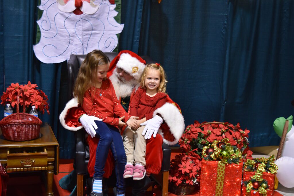 two kids sitting on the lap of santa claus